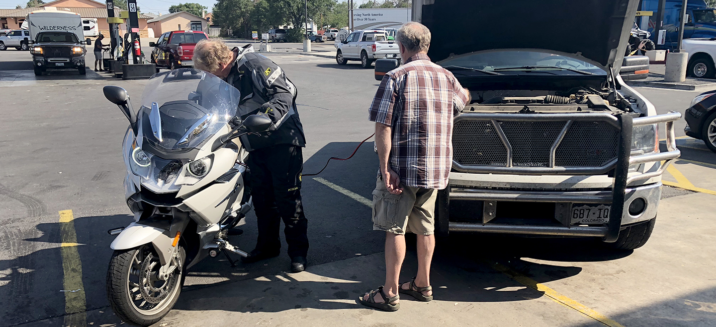 Motorcyle getting a jump from truck in gas station parking lot