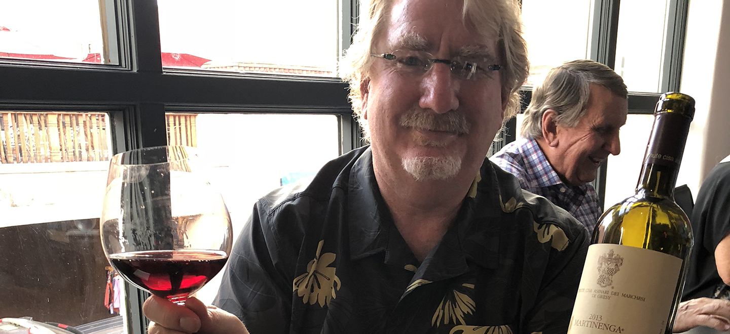 Greg Bannister holding up a bottle of wine in Santa Fe restaurant.